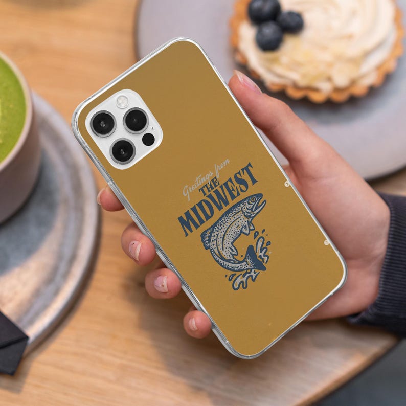 May include: A clear phone case with a yellow background and a graphic of a fish jumping out of the water. The text "Greetings from the Midwest" is printed on the case.