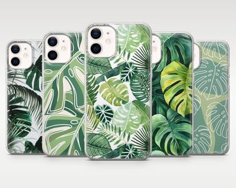 May include: Five phone cases with tropical leaf designs. The cases feature a variety of green leaves, including monstera and palm fronds, against white and green backgrounds. The cases are made of clear plastic.