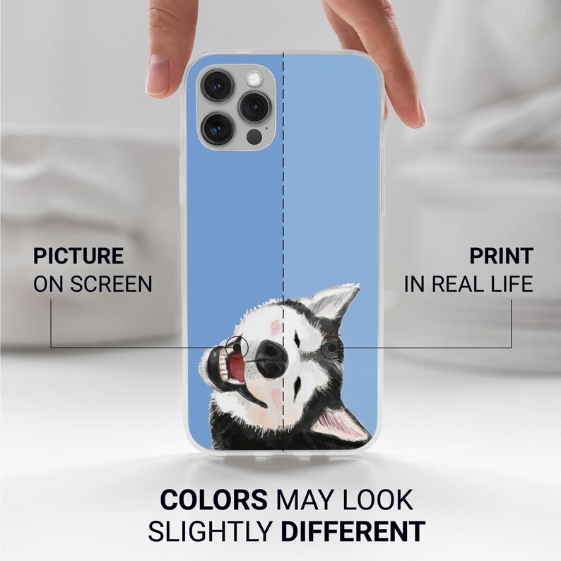 May include: A clear phone case with a blue background and a cartoon image of a black and white husky dog with its tongue sticking out. The text "PICTURE ON SCREEN" and "PRINT IN REAL LIFE" is on either side of the case. The text "COLORS MAY LOOK SLIGHTLY DIFFERENT" is below the case.