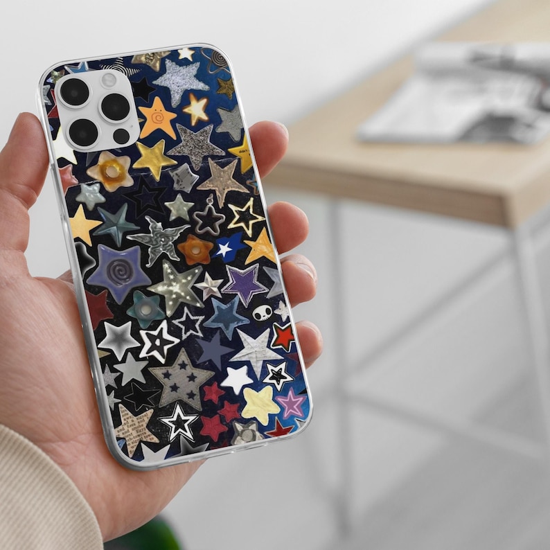 May include: A clear phone case with a colorful star pattern. The stars are various colors, including yellow, blue, silver, and red, and are arranged on a dark blue background. The case has a clear border and a camera cutout.