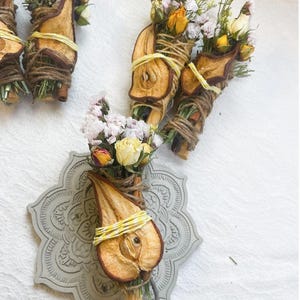 May include: Dried pear, cinnamon sticks, and dried flowers tied together with twine. The bouquet is on a gray, decorative, circular plate.