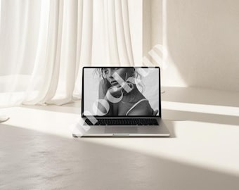 Könnte beinhalten: Ein silberner Laptop mit einem schwarzen Bildschirm, auf dem ein Schwarzweißfoto einer Person zu sehen ist. Der Laptop steht auf einer weißen Oberfläche.