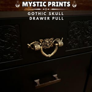 May include: A black drawer with a gold-coloured Gothic skull drawer pull. The pull features a skull within a rose design. The text "MYSTIC PRINTS" and "GOTHIC SKULL DRAWER PULL" are visible.