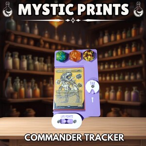May include: A purple Commander Tracker with dice, a card, and a life counter. The text "MYSTIC PRINTS" and "COMMANDER TRACKER" are displayed. The life counter shows the number 10.