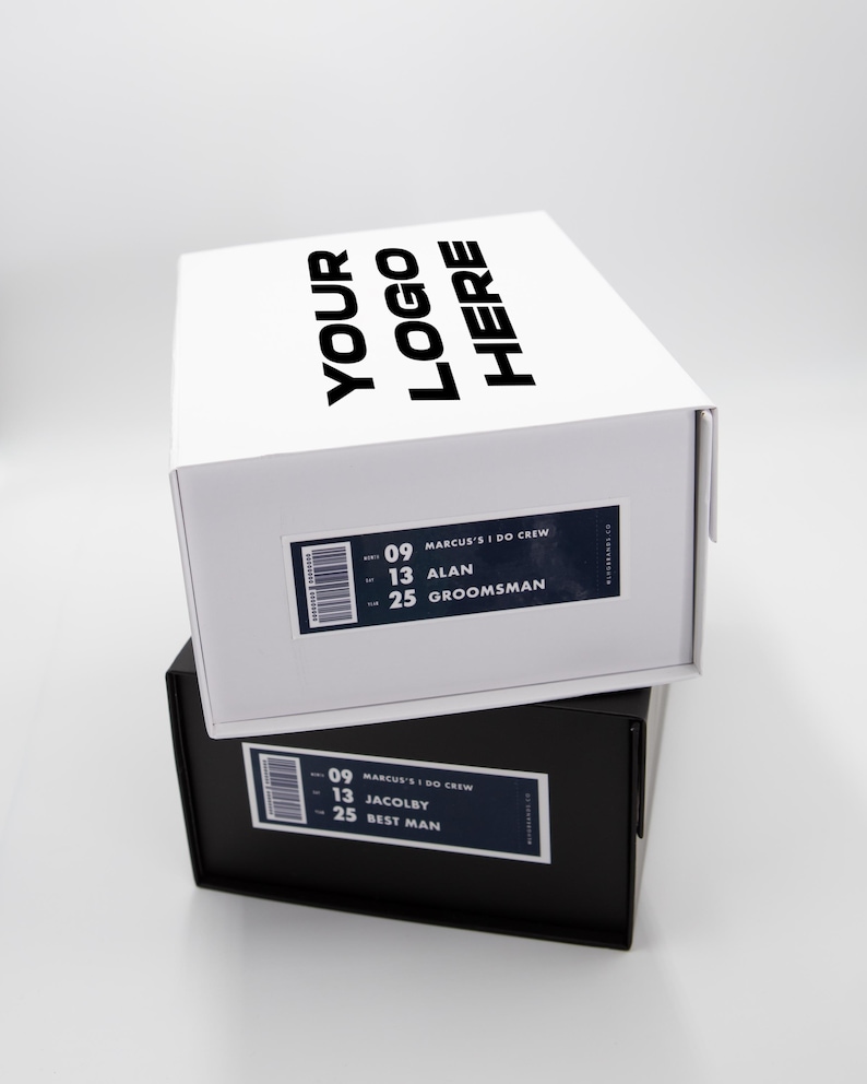 May include: Two stacked shoe boxes, one white and one black. The white box has the text "YOUR LOGO HERE" on the lid. Both boxes have labels with the text "MARCUS'S I DO CREW" and names like "ALAN" and "JACOLBY".
