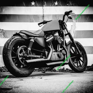 May include: Black and white image of a motorcycle parked in front of a wall with a striped design. The motorcycle has a black frame, tires, and seat. The background features a distressed wall with a star design.