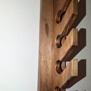 Close-up of staggered front slots on the solid-wood hat rack; smooth edges and visible grain.