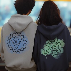 A couple explores a vibrant Asian market, wearing hoodies with large Anahata chakra prints on the back. The man wears black, and the woman wears gray. The scene symbolizes love, balance, and conneсtion