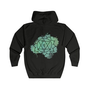 The back of the black hoodie highlights a bold, intricate Anahata chakra design, creating a spiritual and stylish statement piece.