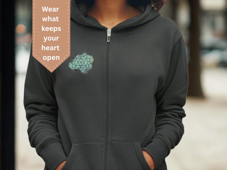 Unisex dark gray zip hoodie with heart chakra mandala design, photographed outdoors. Spiritual clothing inspired by openness, emotional balance and self-connection, perfect for mindful everyday wear.