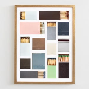 May include: A framed collage of matchboxes with various colors and patterns. The matchboxes are arranged in a grid pattern and contain matches with different colored tips.