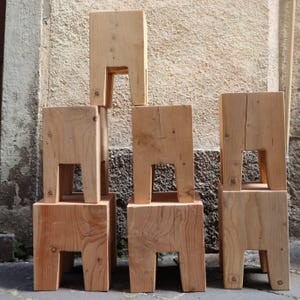 Könnte beinhalten: Ein Satz von sechs Holzhocker, die gestapelt und in einer Reihe angeordnet sind. Die Hocker sind aus Naturholz in hellbrauner Farbe gefertigt. Die Hocker haben ein schlichtes Design mit vier Beinen und einer quadratischen Oberseite.