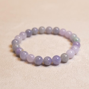 Könnte beinhalten: Ein Armband aus Lavendeljade mit runden Perlen, die in der Farbe von hell bis dunkel Lavendel reichen.