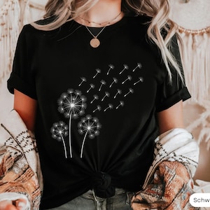 Könnte beinhalten: Schwarzes T-Shirt mit einem weißen Löwenzahnmuster. Der Löwenzahn bläst Samen in den Wind.
