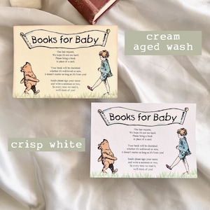 May include: Two cards with a light blue background and white text. The cards have a banner at the top that says "Books for Baby". The cards feature a Winnie the Pooh illustration and a child with a book. The text on the cards asks guests to bring a book instead of a card. The cards are shown on a white surface. One card has a text overlay that says "cream aged wash" and the other card has a text overlay that says "crisp white".