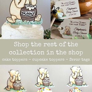 May include: Winnie the Pooh themed baby shower decorations.  A cake topper with Winnie the Pooh holding a honey pot.  Three cupcake toppers with Winnie the Pooh holding a honey pot.  Favor tags with Winnie the Pooh holding a honey pot and the text "A little yummy for your tummy" and "Stephanie's Baby Shower 2/29/20".