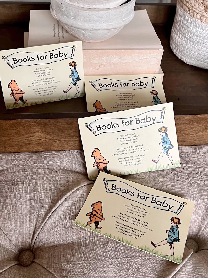 May include: Four colorful cards with a Winnie the Pooh theme. Each card has the text "Books for Baby" and a request to bring a book in place of a card. The cards are decorated with illustrations of Winnie the Pooh and a little girl.