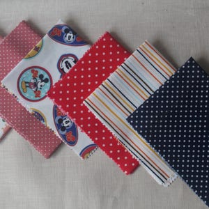 May include: Six fabric squares with different patterns. The squares are pink with white polka dots, white with red and blue polka dots, white with a Mickey Mouse design, red with white polka dots, white and blue stripes, and navy blue with white polka dots.