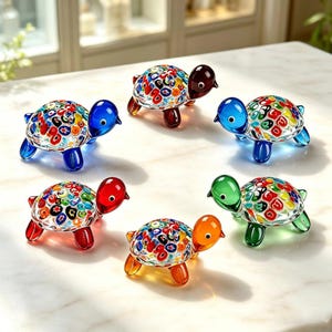 May include: A collection of five glass turtle figurines, each featuring a clear shell with colorful millefiori patterns. The turtles have solid-colored heads and legs in blue, dark brown, red, orange, and green, arranged in a circular formation.