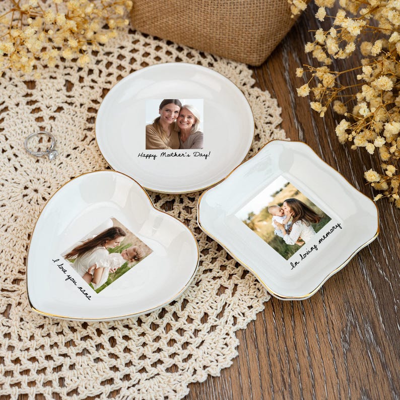 May include: Three white ceramic trinket dishes with gold trim, each featuring a photograph. One is round with "Happy Mother's Day!" text, another heart-shaped with "I love you nana" text, and a square dish with "In loving memory" text.