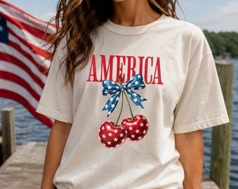 Koszulka America Cherry | Koszulka Coquette z okazji 4 lipca | Koszulka z grafiką z kokardą patriotyczną | Urocza letnia koszulka USA | Koszulka Comfort Colors Cherry
