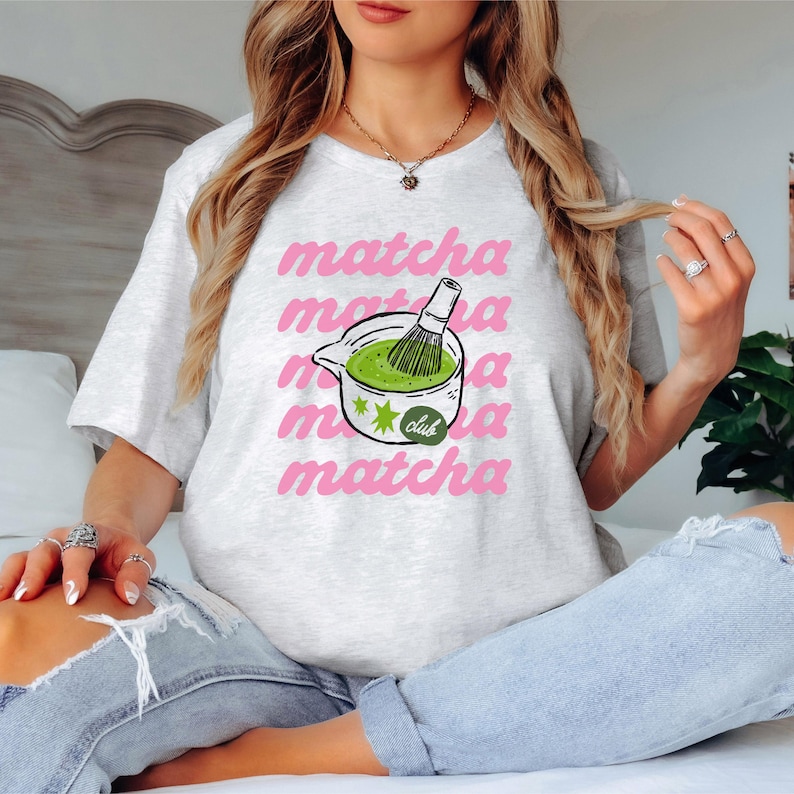 Ash matcha club shirt featuring bold pink typography and matcha drink artwork, perfect tea lover graphic tee for casual cafe outfits.