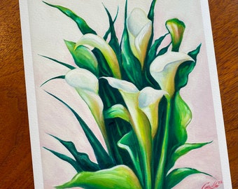 May include: A painting of white calla lilies with green leaves. The flowers are arranged in a bouquet and the background is a light pink.