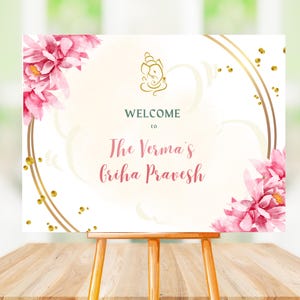 May include: Welcome to The Verma's Griha Pravesh sign with pink floral designs and gold accents.