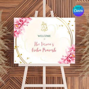 May include: Welcome sign with a white background, gold circles, and pink flowers. The text reads "Welcome to The Verma's Griha Pravesh".