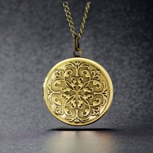 Puede incluir: Un collar de oro con un medallón redondo que presenta un intrincado diseño floral.