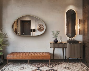 May include: An interior design scene featuring a tufted leather bench, a large oval mirror, and a decorative rug. A small table with a vase and a dark sink with a mirror are also present. The color palette includes browns, golds, and neutral tones.