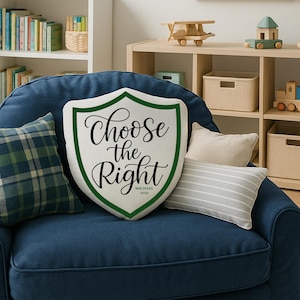 May include: A decorative pillow with a shield shape and the text "Choose the Right" in black script, framed by a green border. The pillow is on a blue armchair, with other pillows and wooden toys in the background.