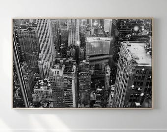 Könnte beinhalten: Ein Schwarzweißfoto einer Skyline mit fallendem Schnee. Das Foto wurde von einem hohen Punkt aus aufgenommen, mit Blick auf die Gebäude. Die Gebäude sind hoch und schlank, mit vielen Fenstern. Der Schnee fällt sanft und erzeugt eine friedliche und ruhige Atmosphäre.