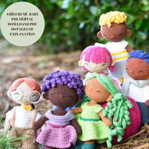 May include: A group of six crocheted dolls with different coloured hair and clothing. The dolls are all smiling and have brown skin. The dolls are sitting on a bed of green leaves. The text "AMIGURUMI BABY PDF DÍJITAL DOWNLOAD PDF 60 PAGES OF EXPLANATION" is visible in the top left corner of the image.