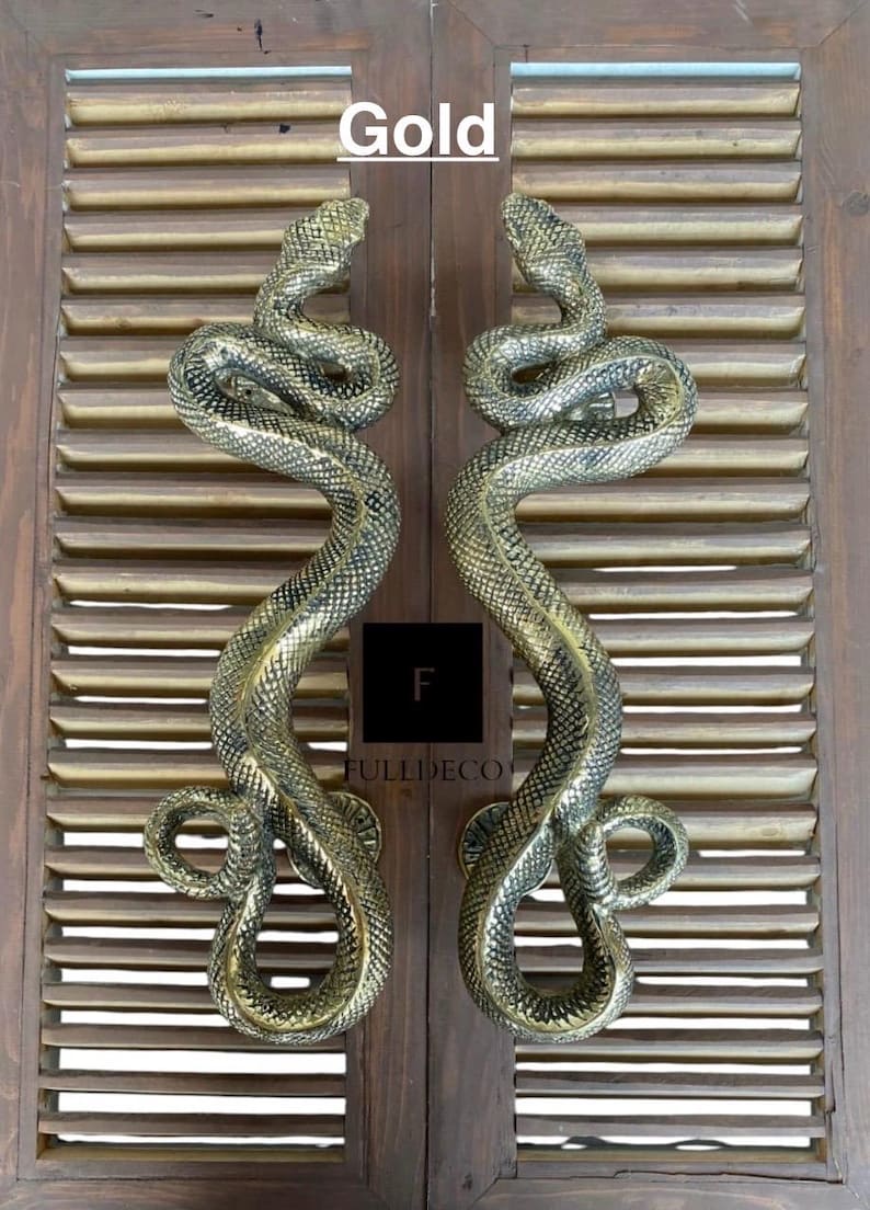 Pu&ograve; includere: Un paio di maniglie per porte a forma di serpente dorate. Le maniglie sono in metallo e hanno un design di serpente realistico. La parola "Gold" &egrave; scritta sopra le maniglie.