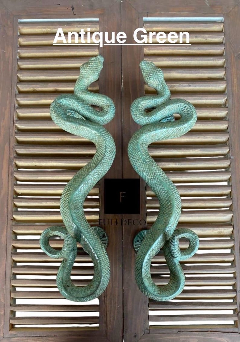 Pu&ograve; includere: Un paio di maniglie per porte a forma di serpente verde antico. Le maniglie sono in metallo e hanno un design di serpente realistico. Le maniglie sono montate su una porta in legno.