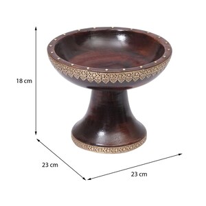 Könnte beinhalten: Eine dunkelbraune Holzschale auf einem Sockel, mit dekorativen goldfarbenen Metallverzierungen am Rand und am Boden. Die Schale ist 18 cm hoch und 23 cm breit.