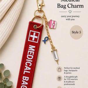 May include: A red rectangular fabric bag tag with white embroidered text reading MEDICAL BAG and a white cross symbol. It features a gold-tone metal lobster clasp, a chain, and three charms: a pink medical kit, a blue ribbon, and a white syringe.