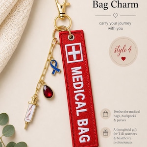May include: A red rectangular embroidered fabric tag with the white text MEDICAL BAG and a white cross symbol. It features a gold-tone lobster clasp, a gold chain, a blue ribbon charm, a red teardrop charm, and a white and gold syringe charm.