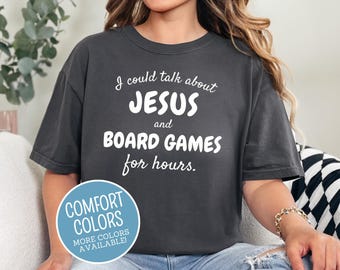 May include: Dark grey t-shirt with the text "I could talk about JESUS and BOARD GAMES for hours." A blue circle with the words "COMFORT COLORS" and "MORE COLORS AVAILABLE!" is on the bottom left.