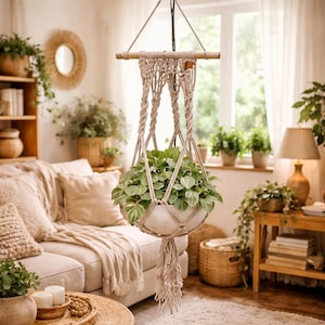 May include: A set of three ceramic mugs with a speckled, cream-colored glaze. Each mug features a different hand-painted design: a blue and green leaf, a yellow flower, and a red berry. The mugs have a simple, rounded shape.