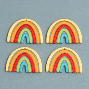 May include: Four colorful rainbow-shaped charms. Each charm features a light yellow outline with a rainbow of colors inside: orange, red, green, and blue. The charms have a small hole at the top for stringing.