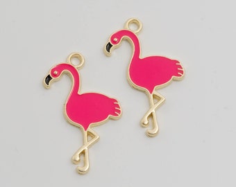 May include: Two gold-colored flamingo charms with pink enamel. The flamingo charms are standing on one leg with their necks curved.