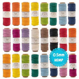 以下が含まれることがあります： 赤、オレンジ、黄色、緑、青、紫など、さまざまな色の麻ひもスプールのコレクションです。各スプールには「HEMP CORD」とサイズ「0.5mm」のラベルが付いています。