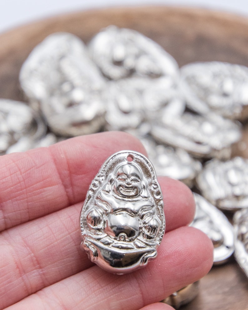 Puede incluir: Encanto de plata con una representaci&oacute;n detallada del Buda de la Risa, un s&iacute;mbolo de buena fortuna y felicidad. El encanto tiene forma ovalada y tiene un agujero en la parte superior para sujetarlo a un collar o pulsera.