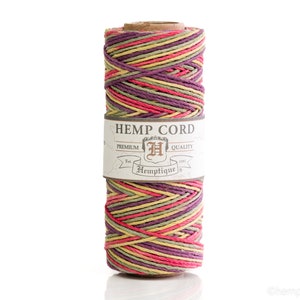 May include: A spool of hemp cord with a mix of colors including red, purple, yellow, and green. The label reads "HEMP CORD" and "Premium Quality" with the brand name "Hemptique". The cord is tightly wound.