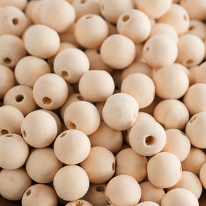 Peut inclure: Gros plan sur un bol rempli de perles en bois naturel. Les perles sont rondes et ont une finition lisse de couleur brun clair. Elles sont parfaites pour les projets d'artisanat.