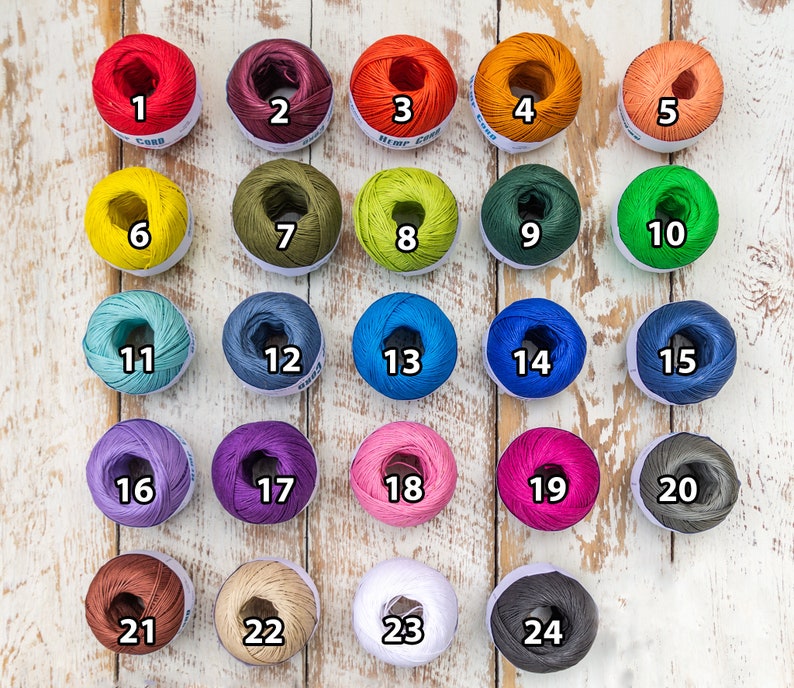 May include: Twenty-four balls of yarn in various colors, numbered 1 through 24. The yarn is wound into balls and arranged in rows on a white wooden surface.