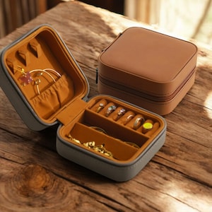 May include: Two gray and brown jewelry boxes with compartments for rings, earrings, and necklaces. The boxes are open and the compartments are filled with jewelry.