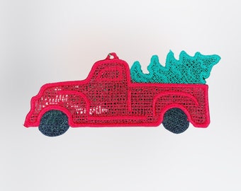 Pode incluir: Caminhão vermelho de estilo vintage com uma árvore de Natal verde na caçamba. O caminhão tem uma cabine arredondada e uma plataforma. O caminhão e a árvore são feitos de tecido e têm um design costurado.
